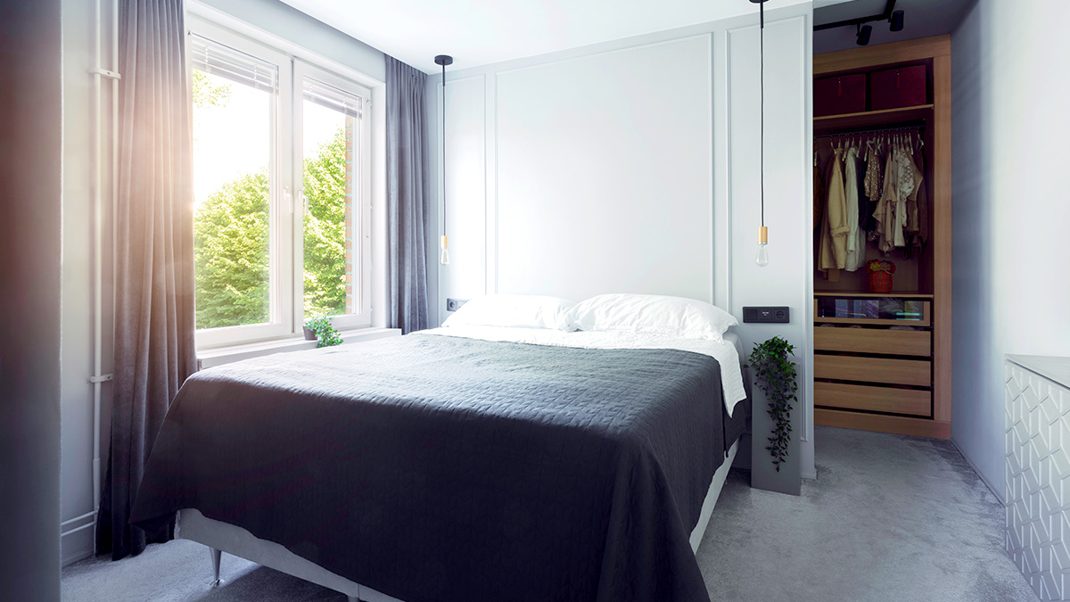 Ein Doppelbett am Fenster, dahinter eine Wand für die Ankleide