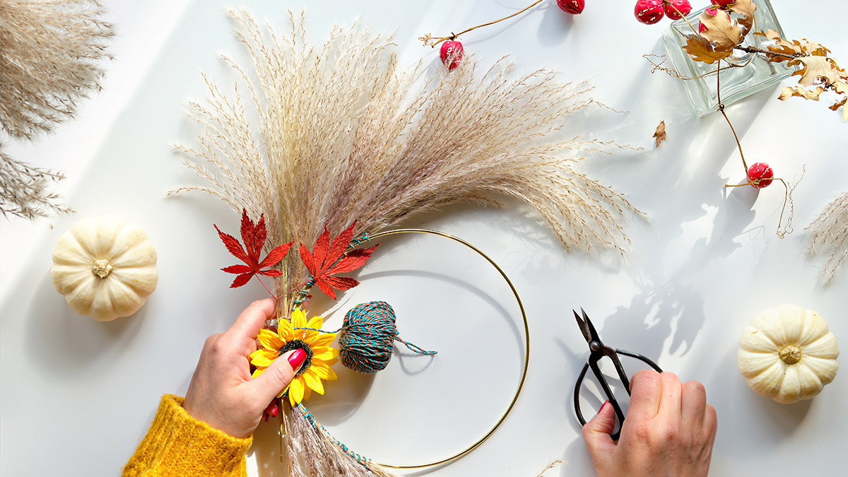 Ein Herbstkrank mit Gräsern, Blättern und Blüten wird gewickelt.