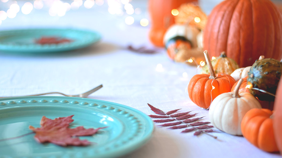 Dekorierter Tisch mit Kürbissen und Blättern.