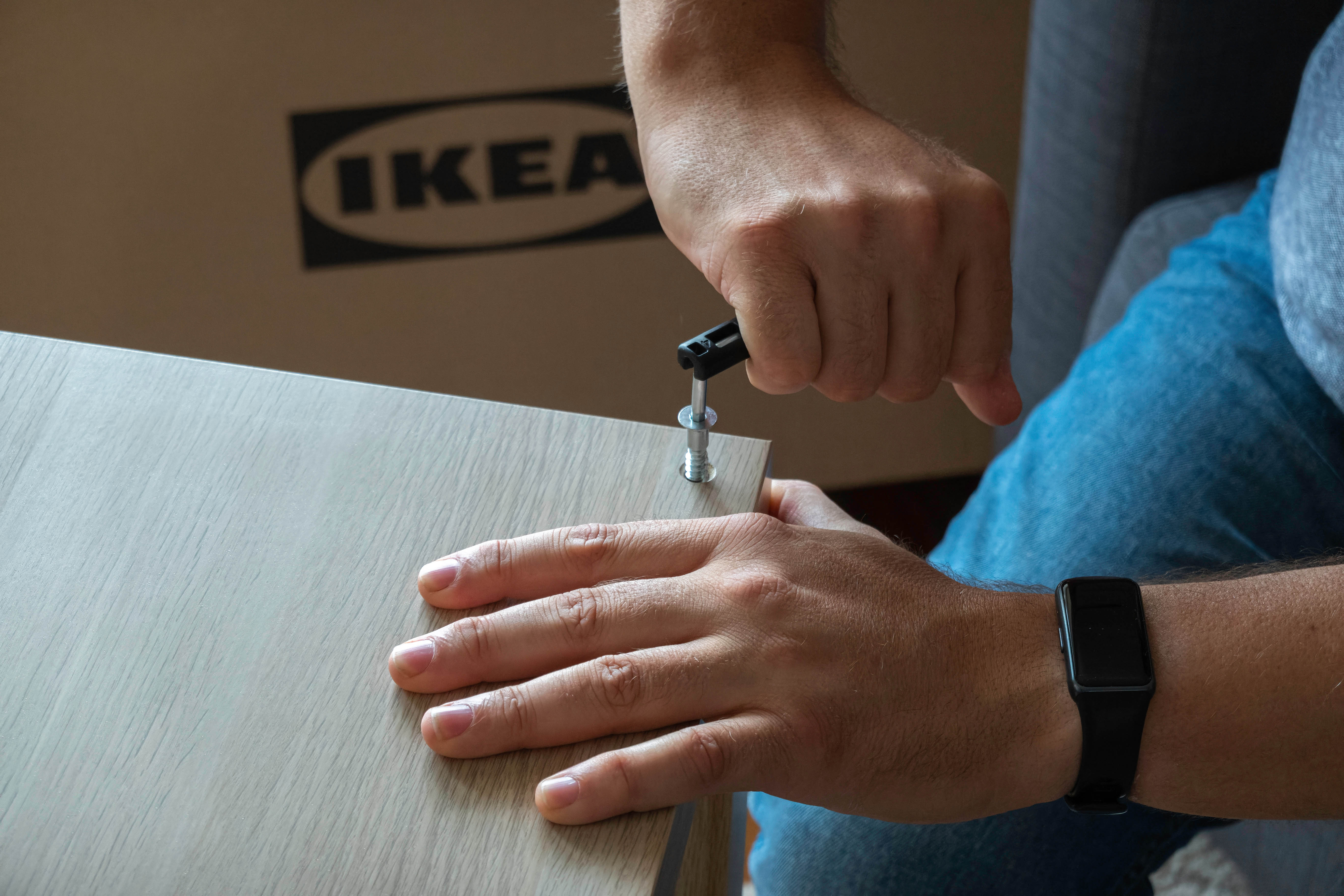 Mann baut Ikea-Regal mit den IKEA-typischen Schrauben und Holzdübeln auf