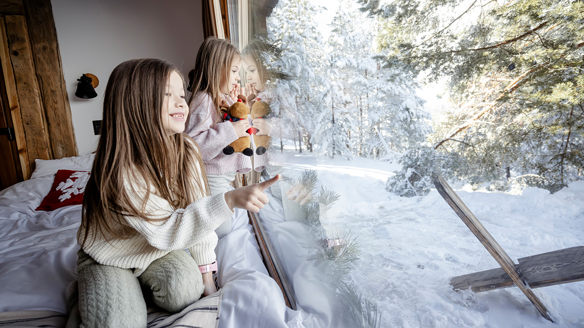Heizung kalte Winter, zwei Kinder schauen von innen nach außen in den verschneiten Garten
