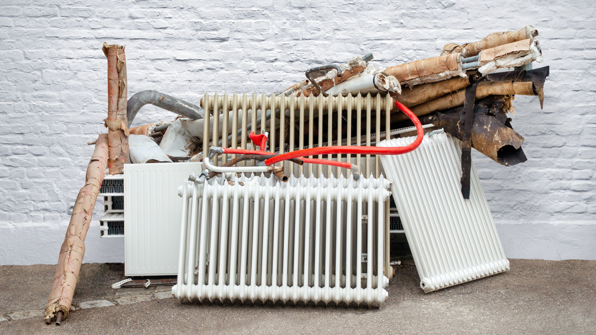 Heizungstausch, alte Heizung und Heizkörper stehen ausgebaut an der Straße