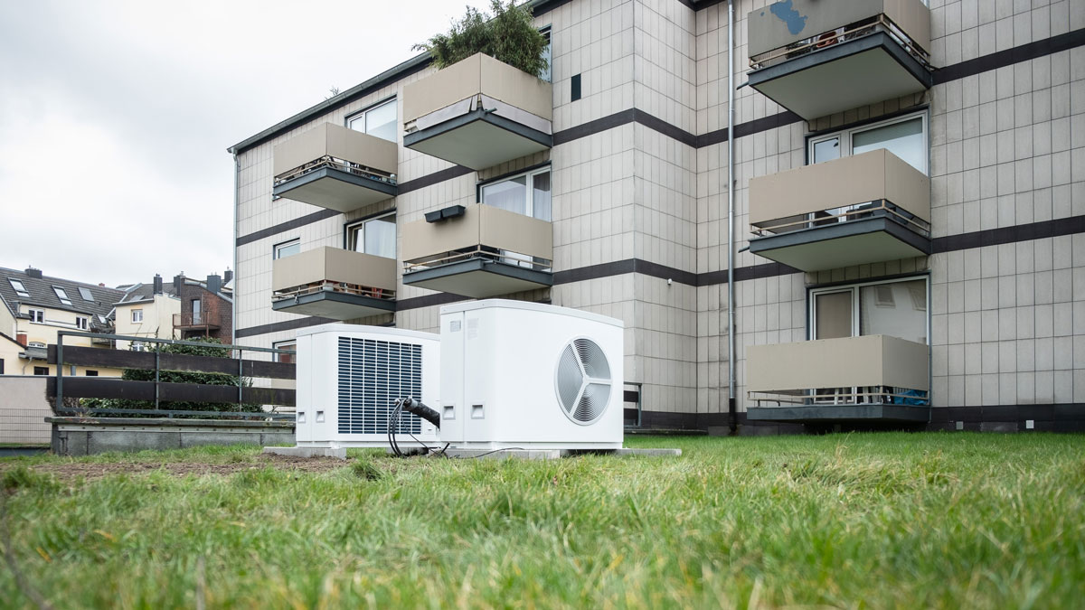 Wärmepumpe Altbau, zwei Wärmepumpen vor einem Altbau-Mehrfamilienhaus