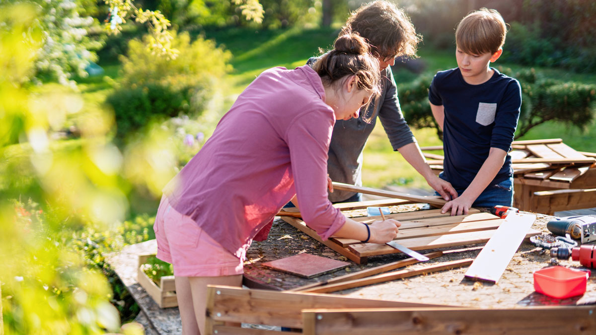 DIY WE, Mutter, Vater und Sohn bauen etwas aus Holz im Garten