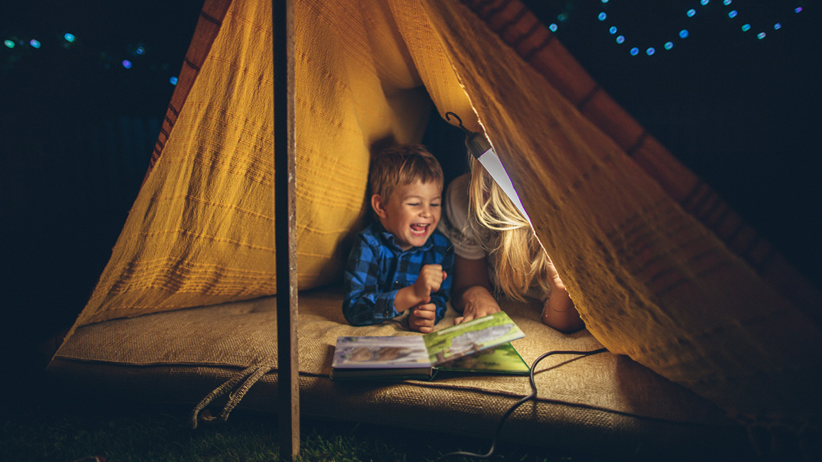 Ein Junge und eine Frau liegen in einem Zelt und lesen ein Buch