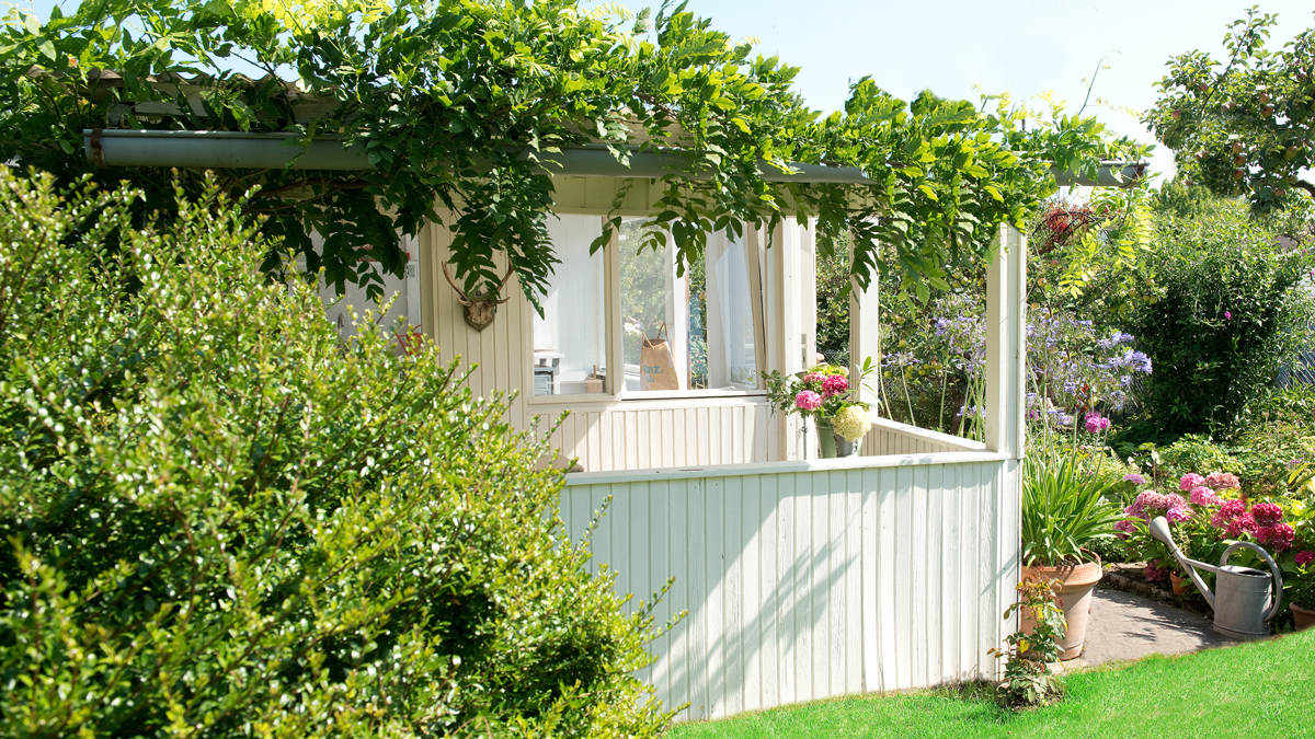 Weiße Laube im Schrebergarten mit Blätterdach