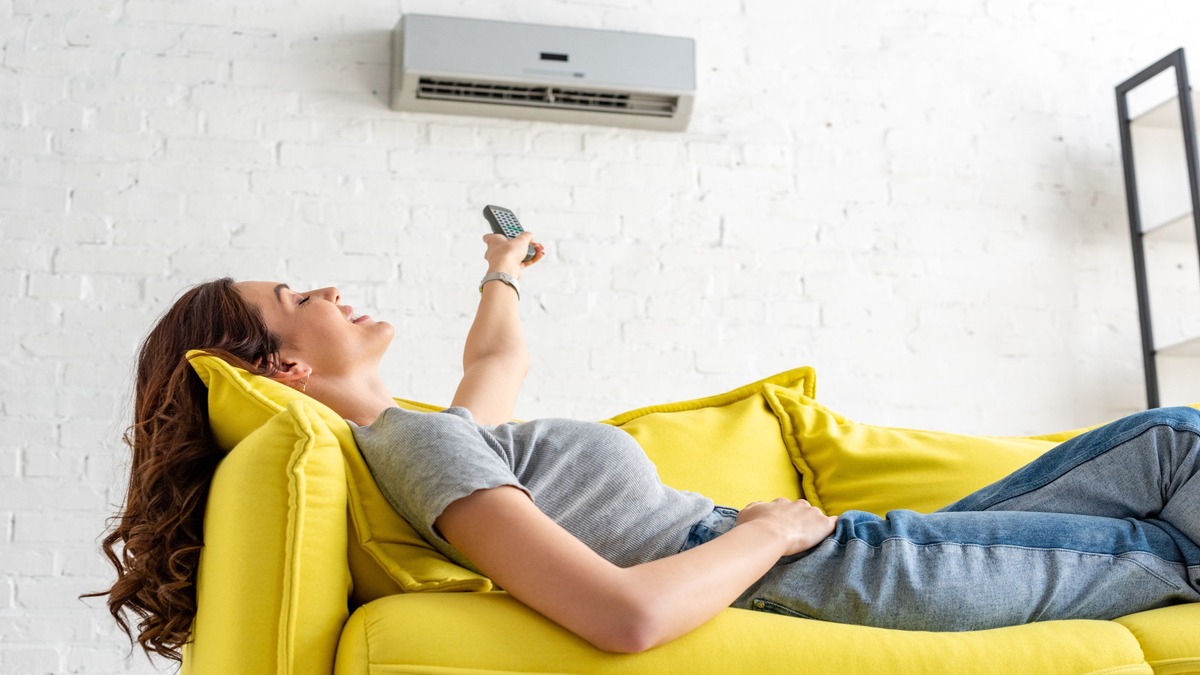 Eine Frau liegt auf einem Sofa unter der Klimaanlage