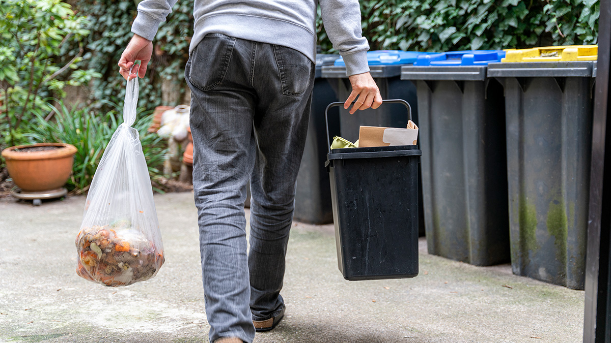 Ein Mann trägt seinen Müll zu den Mülltonnen