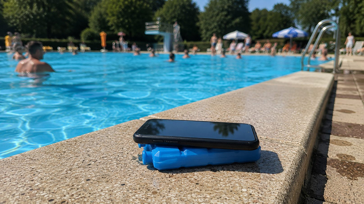 Ein Handy liegt im Freibad auf einem Kühlakku.