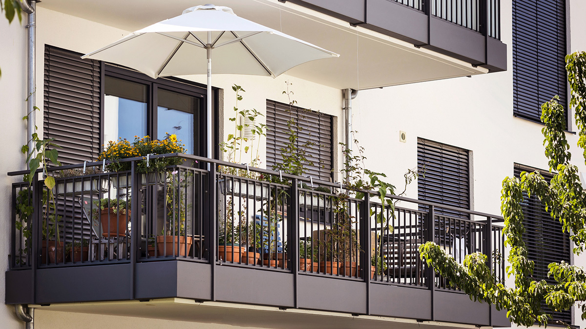 Ein Balkon mit Sonnenschirm und Pflanzen.