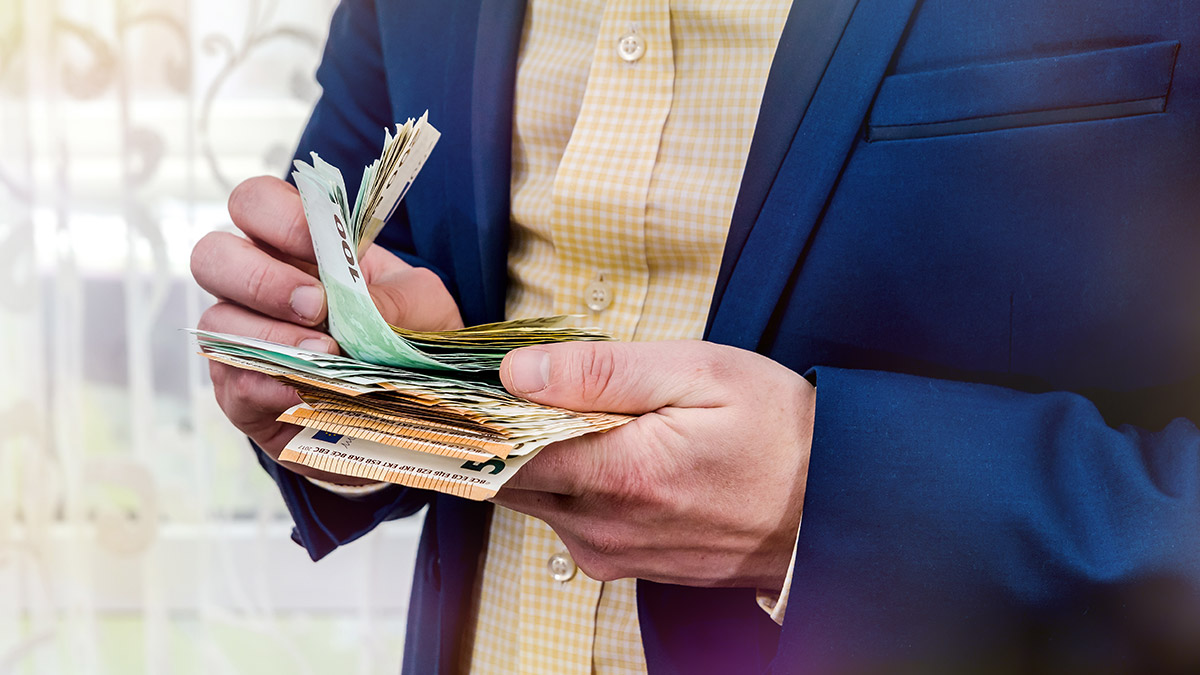 Mann im Sako mit Geldscheinen in der Hand