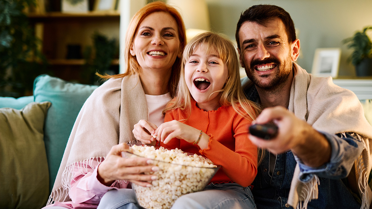 Eine Familie sitzt auf dem Sofa mit Popcorn