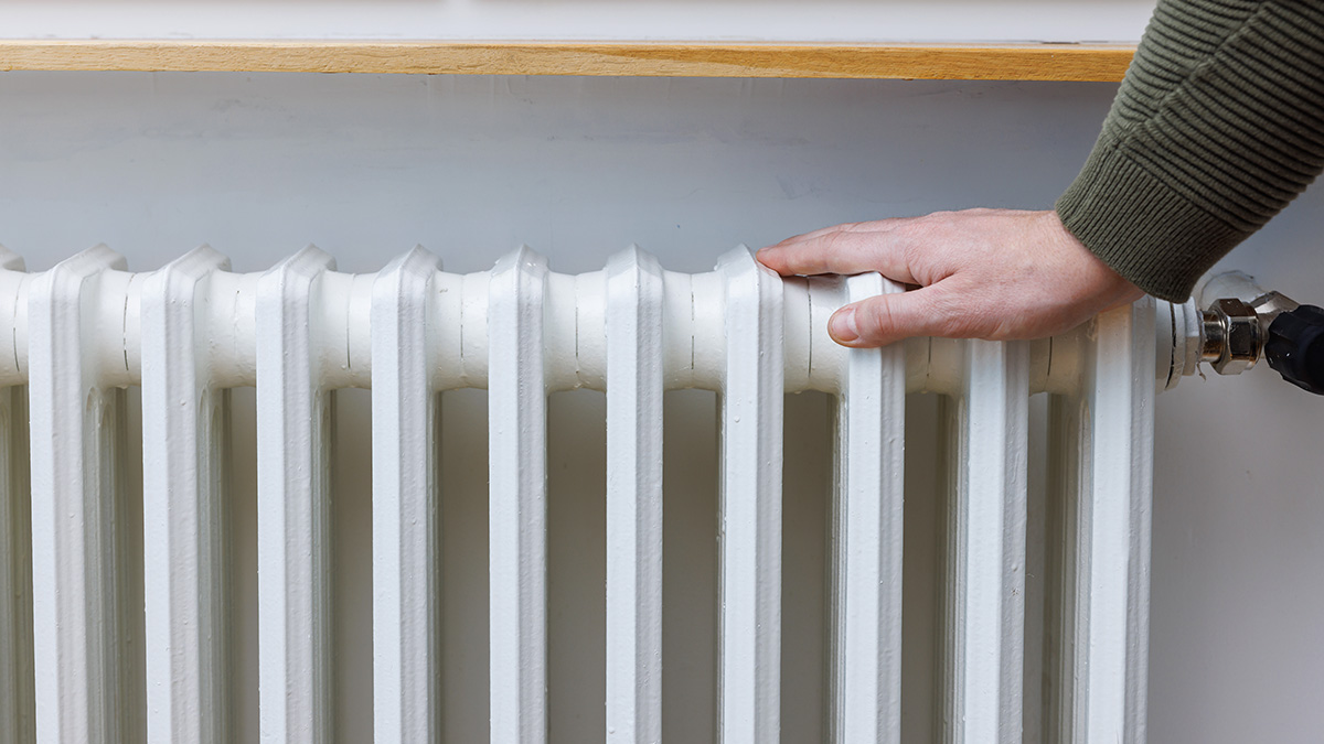 Hand wärmt sich am Heizkörper