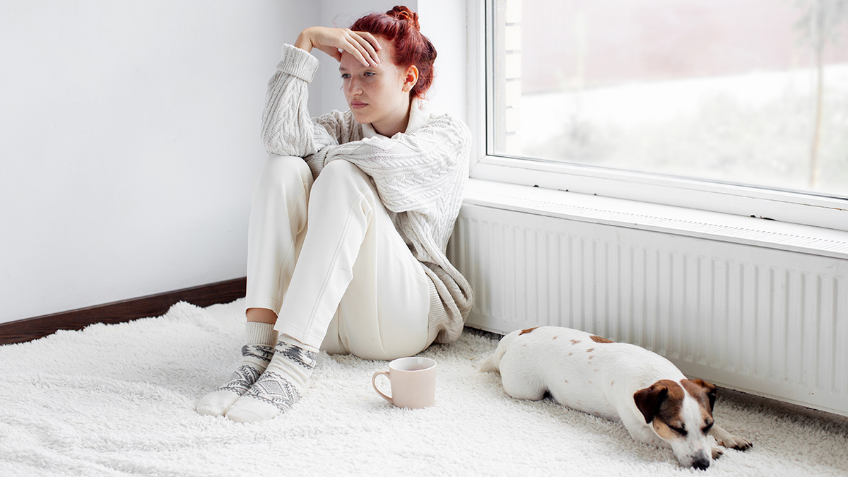 Trockene Heizungsluft, Frau und Hund sitzen vor Heizung
