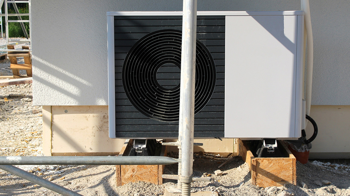 Wärmepumpe vor einem Neubau.