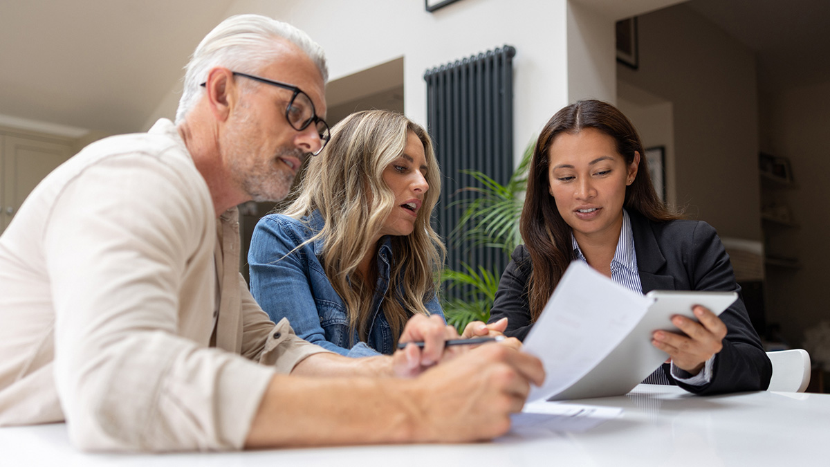 Ein Mann und zwei Frauen lesen ein Dokument durch