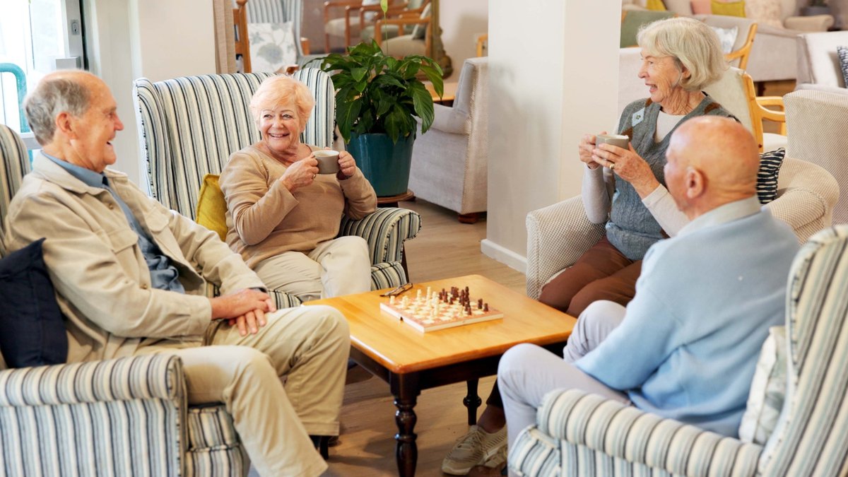 Zwei Seniorinnen und zwei Senioren sitzen gemütlich an einem Tisch