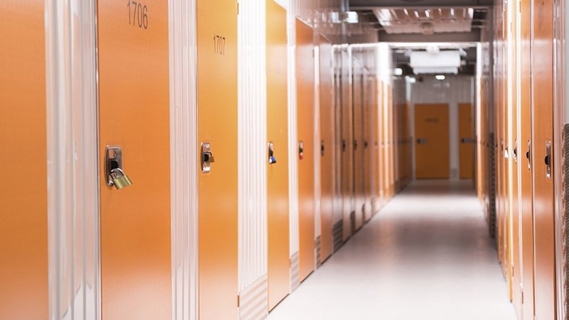 Möbeleinlagerung, Gang eines Selfstorage-Lagers mit orangefarbenen Türen