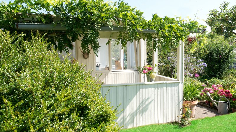 Weiße Laube im Schrebergarten mit Blätterdach