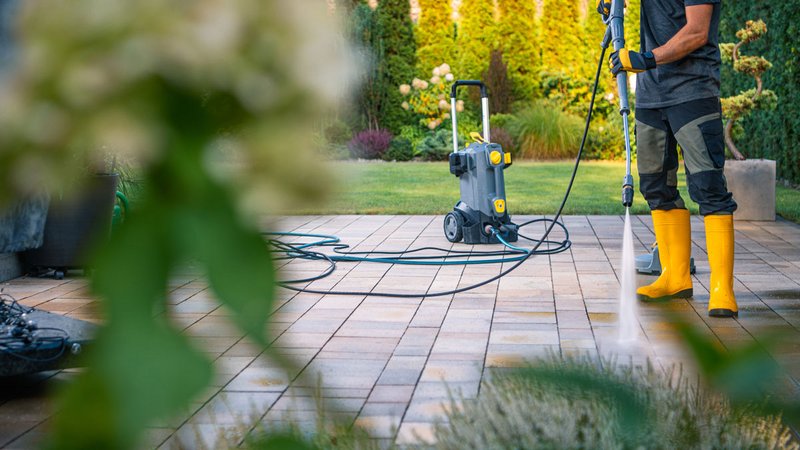 Terrasse reinigen, Mann reinigt Terrasse mit Hochdruckreiniger