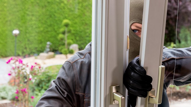 Einbruchschutz Urlaub, Einbrecher im Sommer vor geöffnetem Fenster