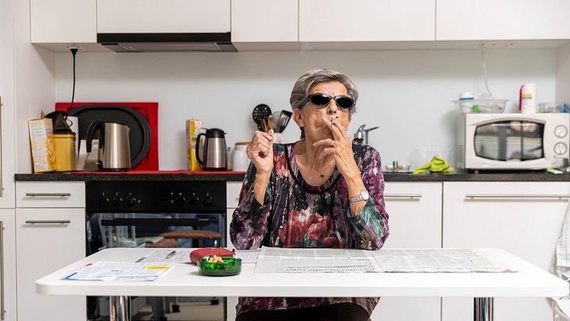 Vormieter Raucher, ältere Frau mit Sonnenbrille sitz am Küchentisch und raucht
