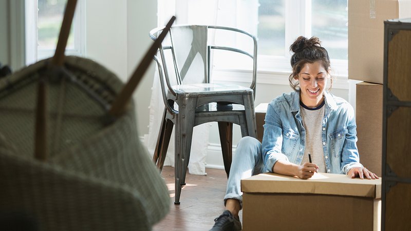 Umzug Checkliste, Frau sitzt auf dem Boden und beschriftet einen Umzugskarton, Foto: kali9 / iStock.com