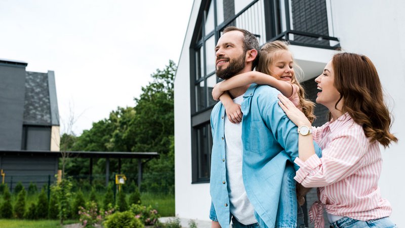 Förderprogramme Familien, junge Familie (Mutter, Vater, Kind) vor einem Neubau