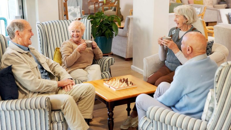 Zwei Seniorinnen und zwei Senioren sitzen gemütlich an einem Tisch
