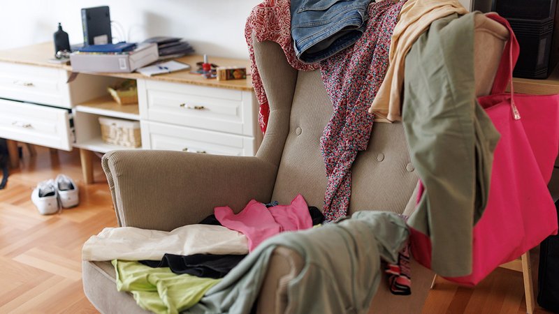 Ein Sessel voll mit Klamotten und einer Handtasche