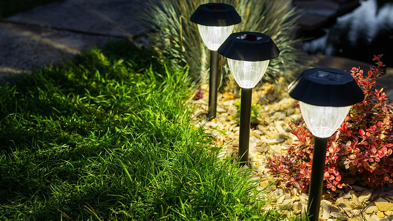 Drei Solarleuchten beleuchten nachts die Beetkante.