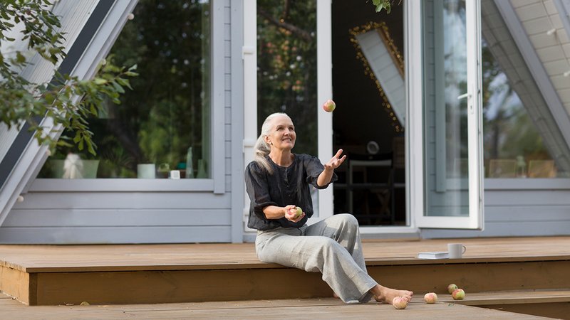 Tiny House Siedlung Senioren, Seniorin sitzt vor ihrem Tiny House und freut sich