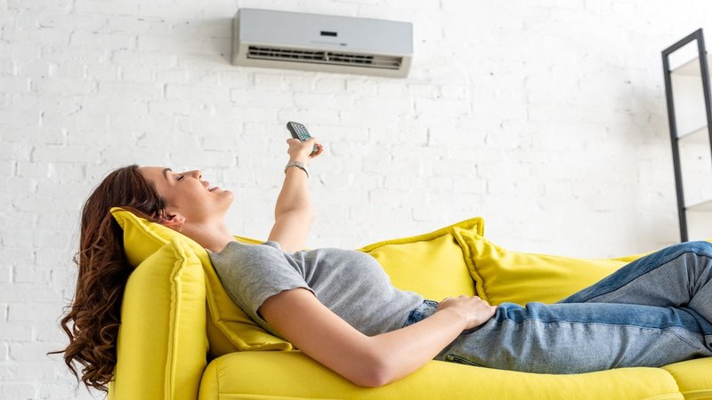 Eine Frau liegt auf einem Sofa unter der Klimaanlage