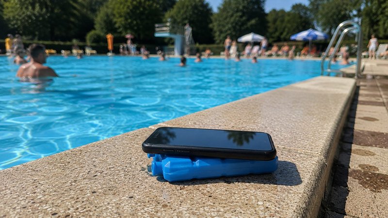 Ein Handy liegt im Freibad auf einem Kühlakku.