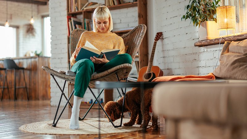 PM Wohnkompromisse, Frau sitzt zufrieden in ihrer Wohnung und liest