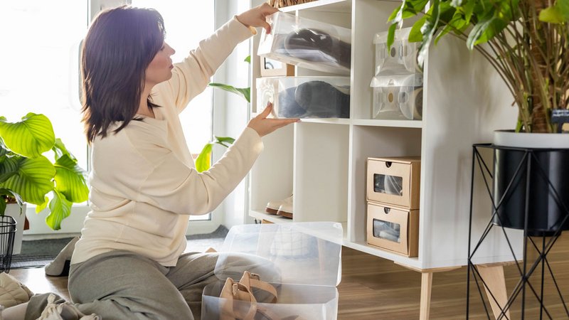 Tipps aufgeräumtes Zuhause, Frau sortiert ihre Schuhe in Boxen