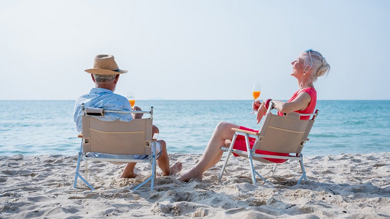 Ruhestand im Ausland, Rentnerehepaar sitzt im Stuhl am Strand und genießt den Ruhestand