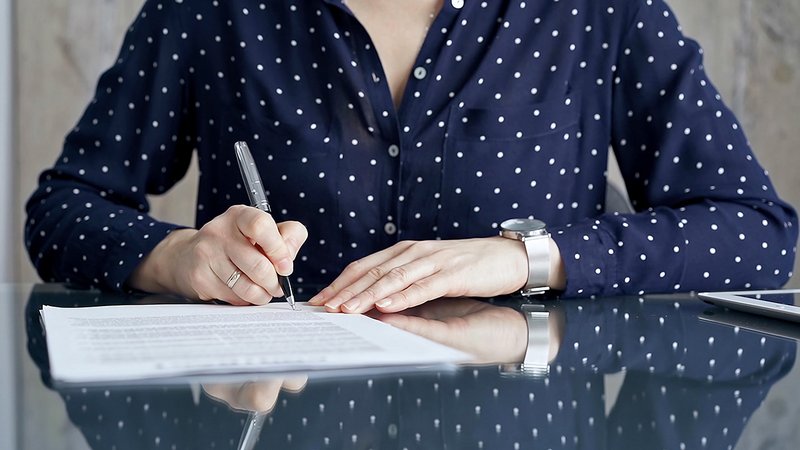 Mieterhöhung Zustimmung Mieter, Mieterin sitzt am Tisch und unterschreibt eine Mieterhöhung