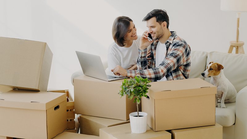 Internet & Telefon ummelden, Paar sitzt mit Laptop und Telefon zwischen Umzugskartons