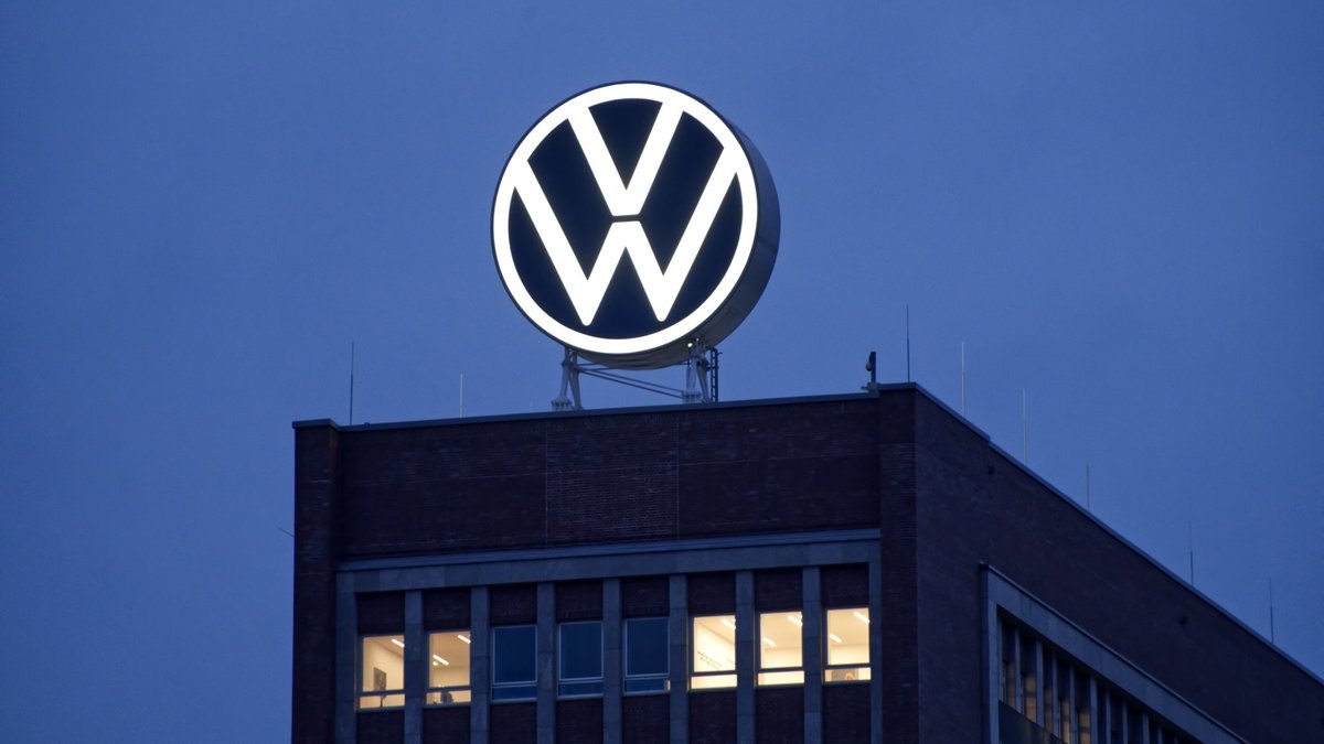 VW-Logo auf einem Werksgebäude vor blauem Himmel