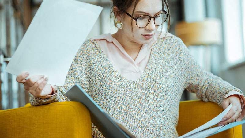 Heizkostenabrechnung prüfen, Frau sieht sich Dokumente in einem Ordner an