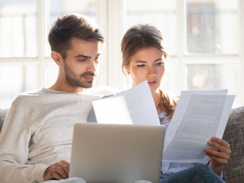 Heizkostenabrechnung prüfen, Mann und Frau sitzen am Laptop und prüfen Dokumente