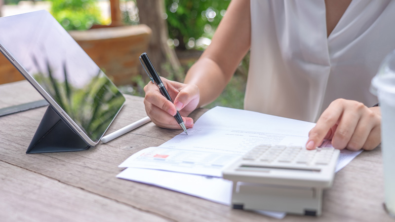 Heizkosten abrechnen, Frau rechnet Werte auf einem Dokument nach