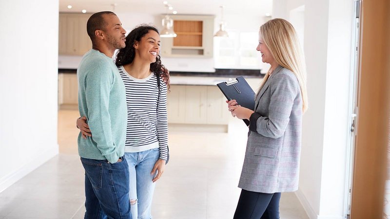 Paar spricht mit Vermieterin, die ein Klemmbrett in der Hand hält