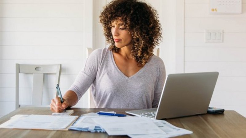 Eine Frau sitzt mir ihren Unterlagen vor einem Laptop.