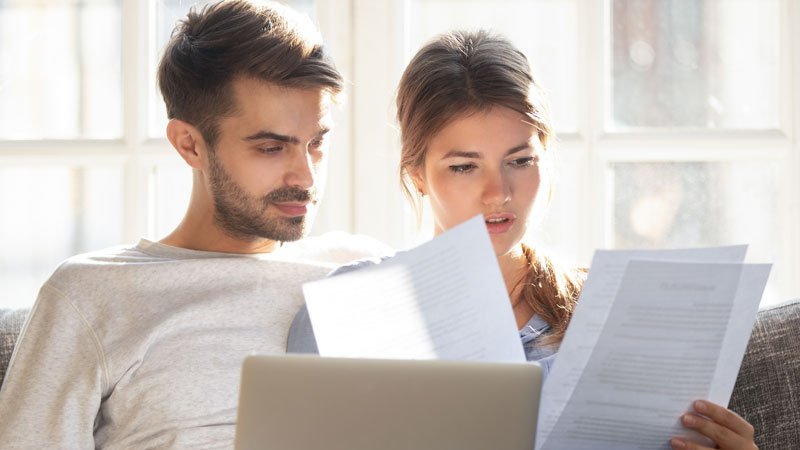 Heizkostenabrechnung prüfen, Mann und Frau sitzen am Laptop und prüfen Dokumente