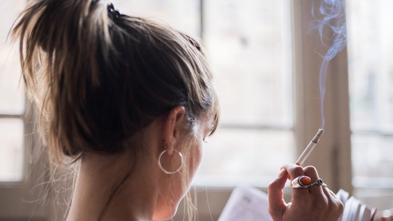 Eine Frau liest ein Buch und raucht