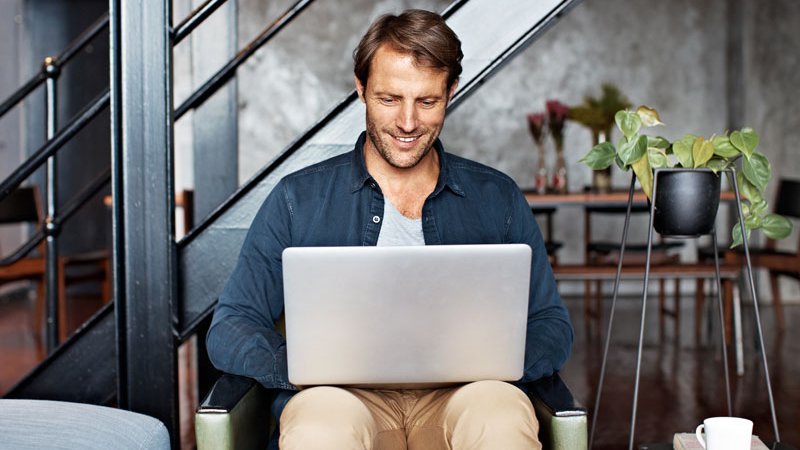 Mängelanzeige, Mann sitzt mit Laptop auf seinem Schoß in einem Sessel, 