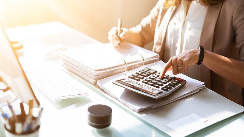 Frau rechnet am Tisch mit Taschenrechner