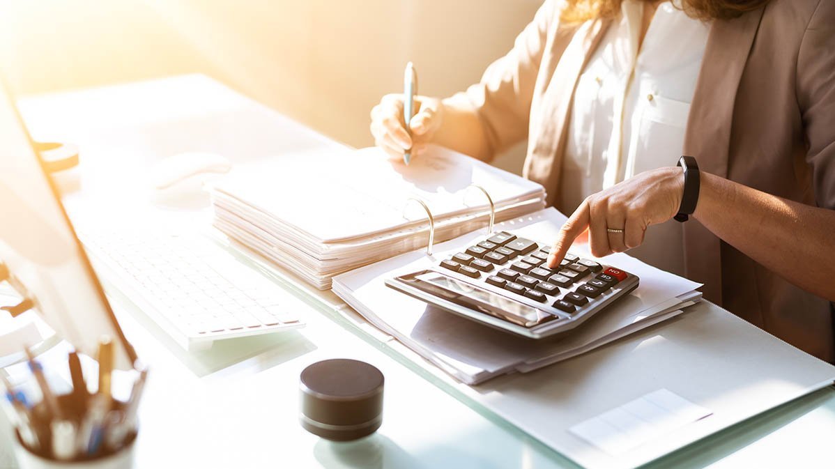 Frau rechnet am Tisch mit Taschenrechner
